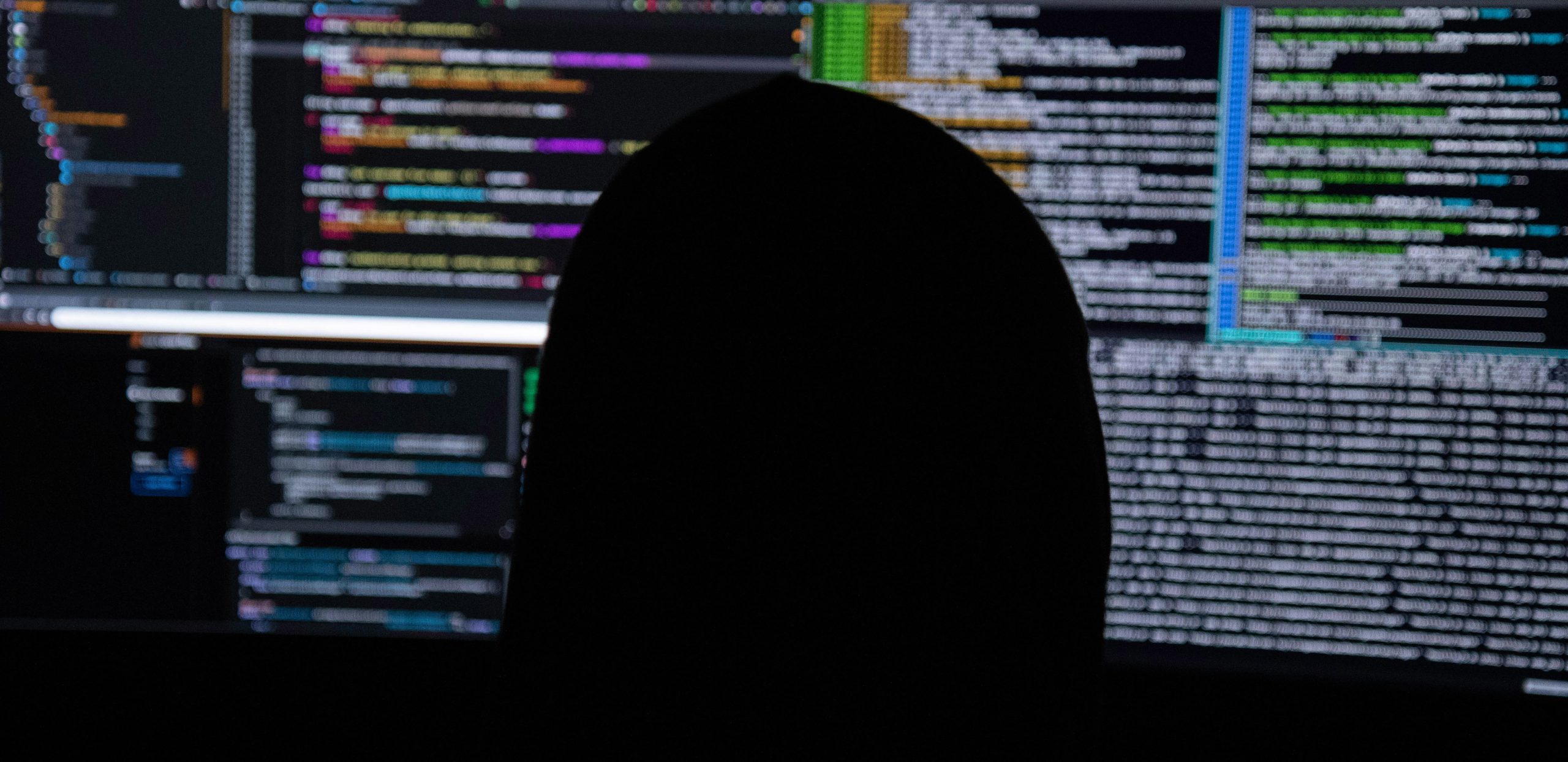 hacker looking at his screens with data on